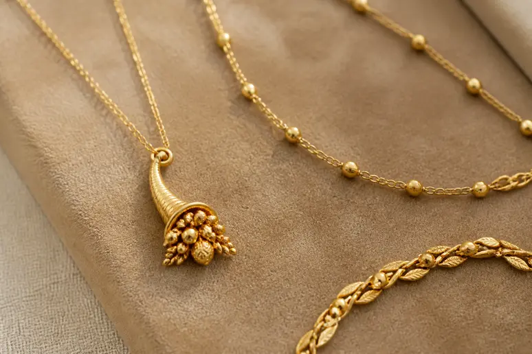 Bijoux raffinés, dont un pendentif corne d'abondance, évoquant la prospérité et l'élégance.
