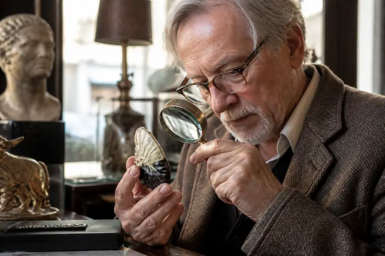 Un antiquaire parisien examine attentivement un objet Art Déco, révélant des détails subtils d'une pièce authentique.