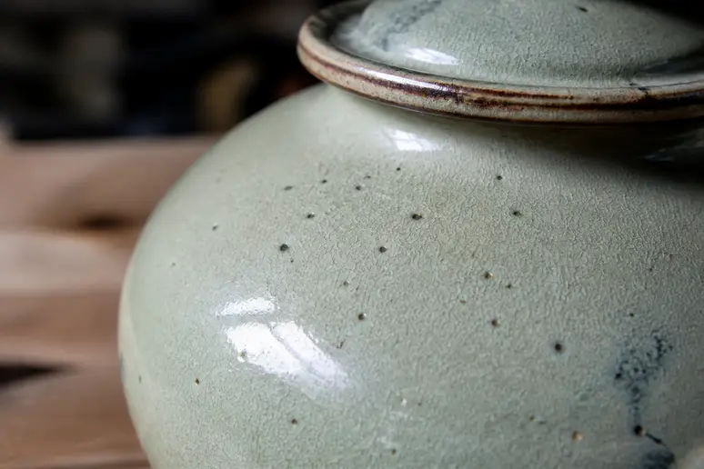 Gros plan sur une potiche en céramique révélant des défauts de 'pinholes' sur l'émail.