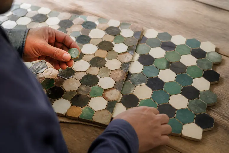 Carreaux de zellige artisanal marocain et imitations en grès cérame posés sur un établi