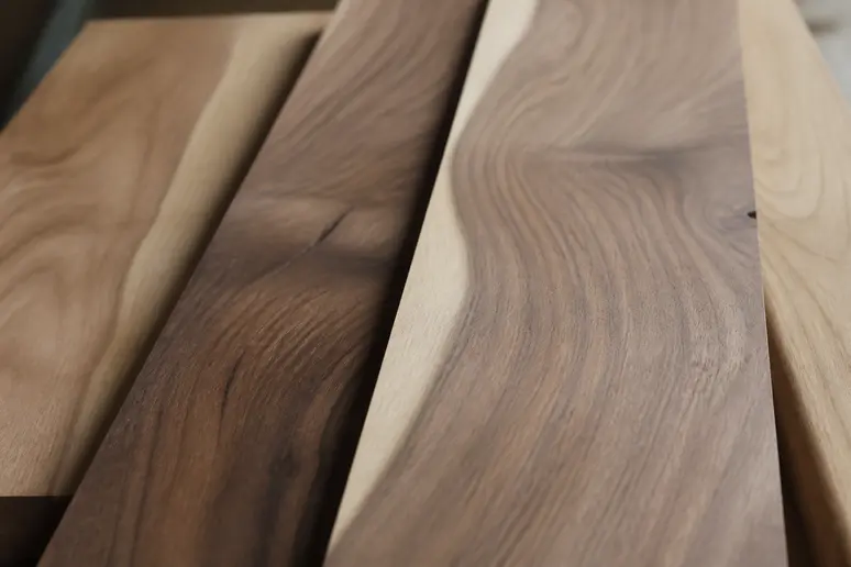 Planches de bois brut révélant le veinage et les nuances de la couleur noyer