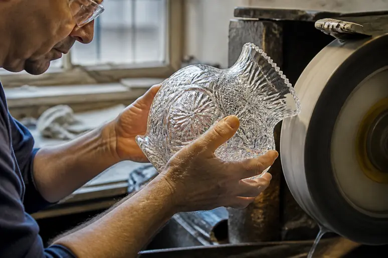 Artisan taillant un cristal de Bohême sur une meule de polissage dans un atelier traditionnel