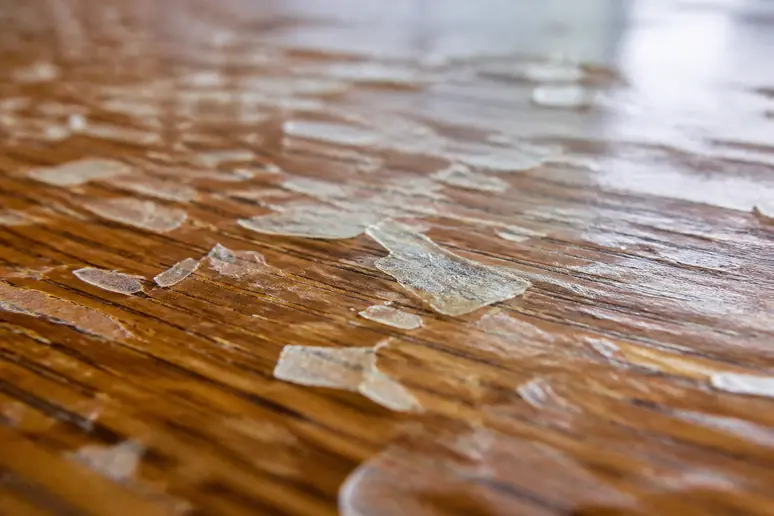 Vernis d'un meuble en bois qui se détache en fines lamelles transparentes