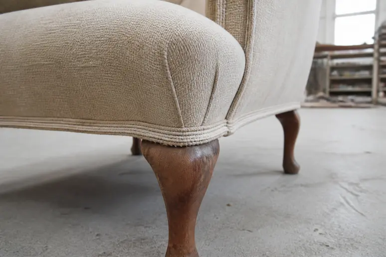 Détails des coutures et du tissu d'un fauteuil crapaud vintage ancien dans un atelier