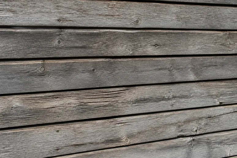 Planches de bois extérieur grises et abîmées nécessitant une rénovation adaptée