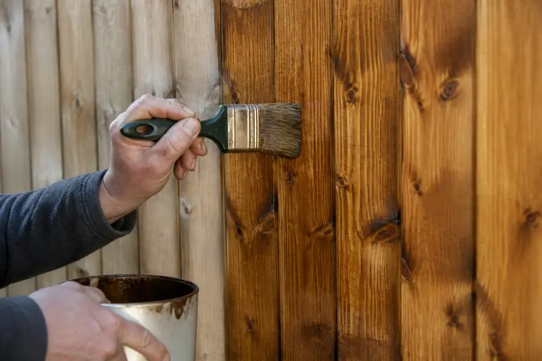 Application minutieuse d'une protection sur une surface en bois vertical