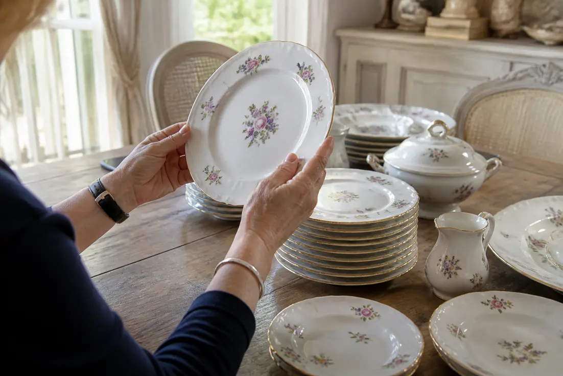 Examen minutieux d'une assiette ancienne en porcelaine de sologne sur une table en bois