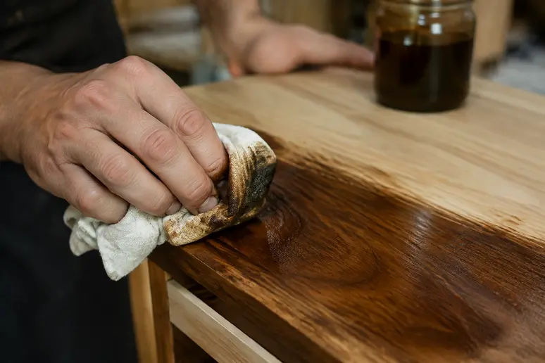 Application au chiffon d'une patine moderne sur un meuble en bois