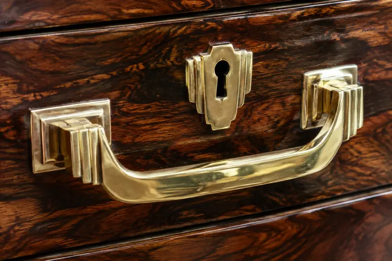 Poignée de meuble art deco en laiton poli montée sur un panneau en bois précieux