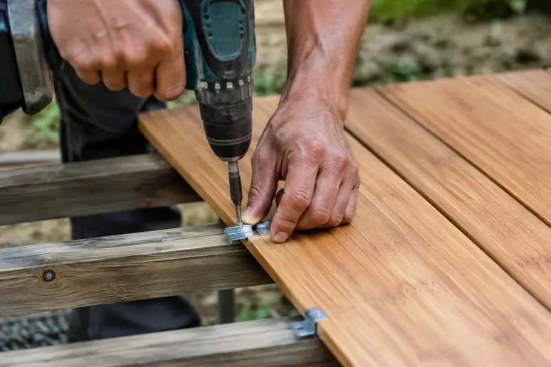 Pose de lames de terrasse bambou avec des clips de fixation vissés sur la structure